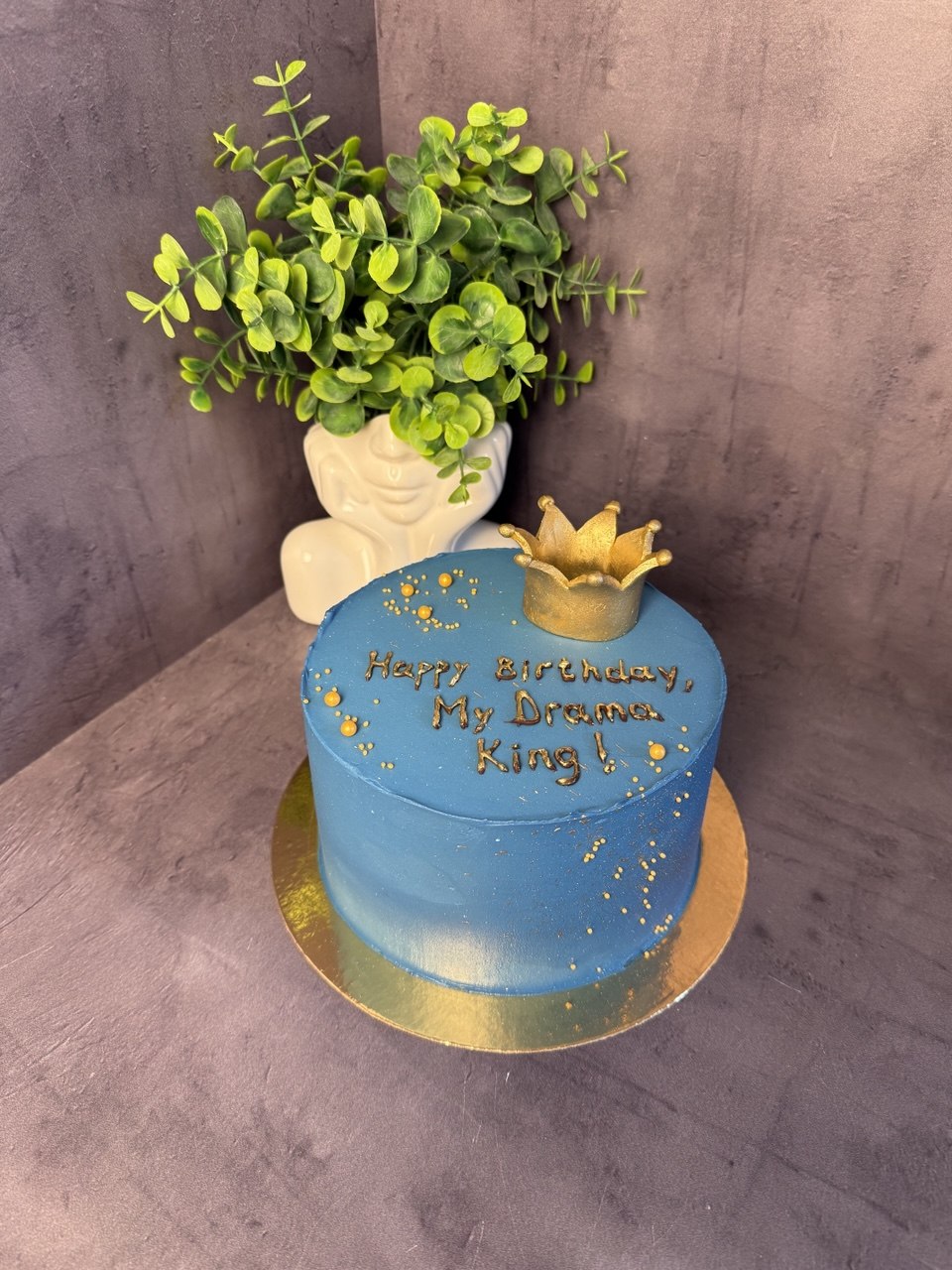 Blue birthday cake with gold crown topper
