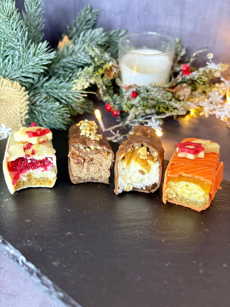 Four Christmas mousse bars with different glazes on slate