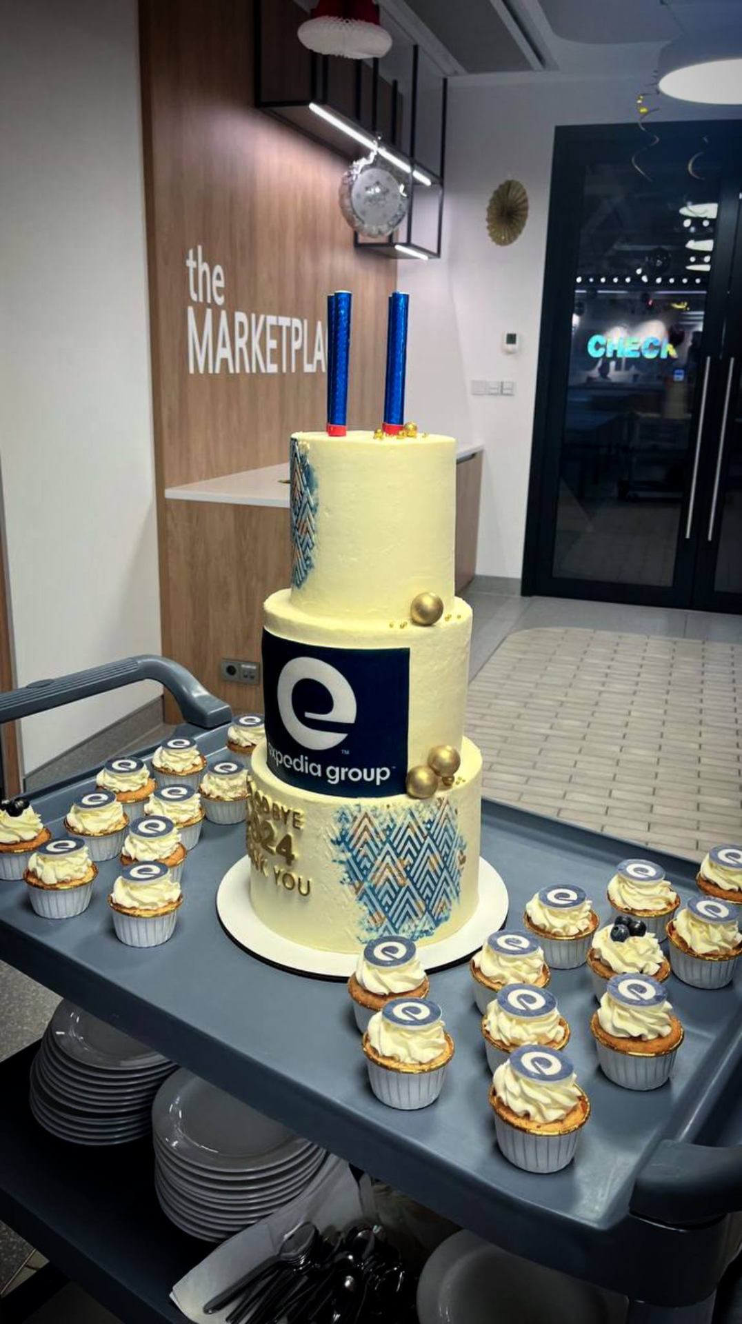 Expedia Group three-tier cake with matching branded cupcakes on catering cart