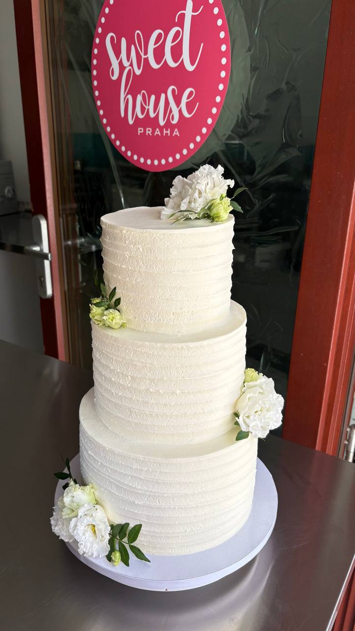 Three-tier white wedding cake at Sweet House Praha storefront