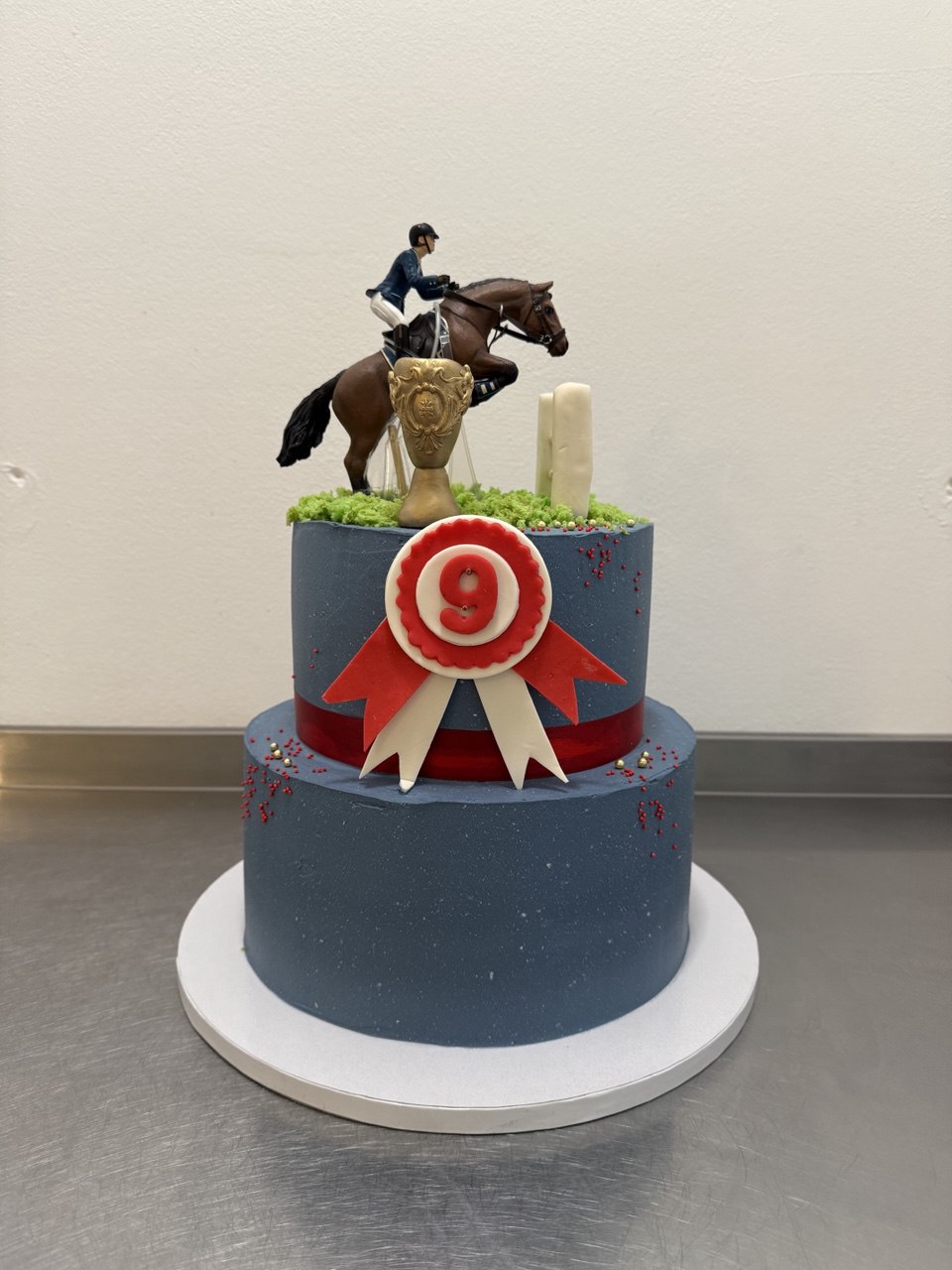 Two-tier navy equestrian 9th birthday cake with horse rider topper