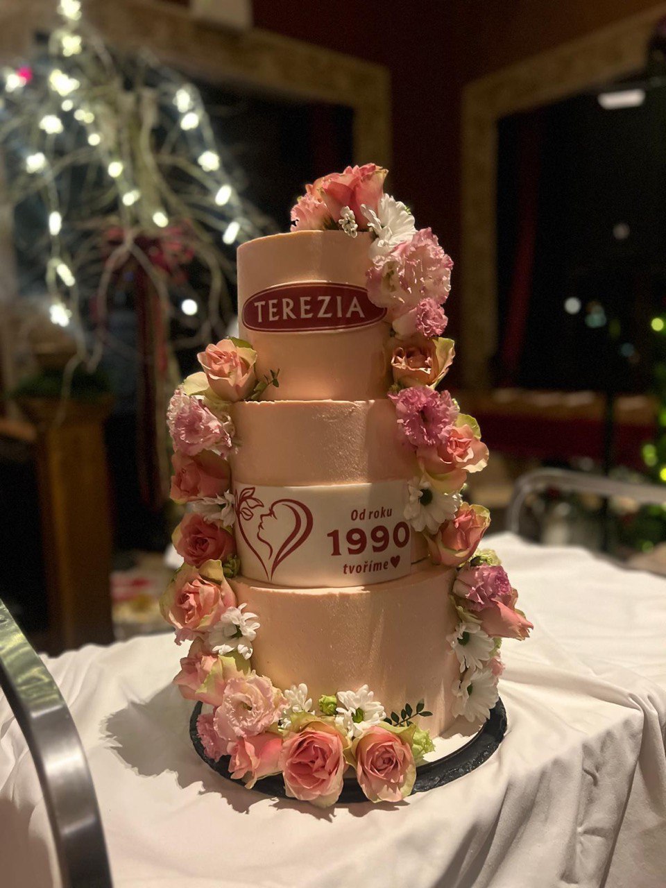 Rose gold three-tier Terezia 1990 anniversary corporate cake with fresh flowers